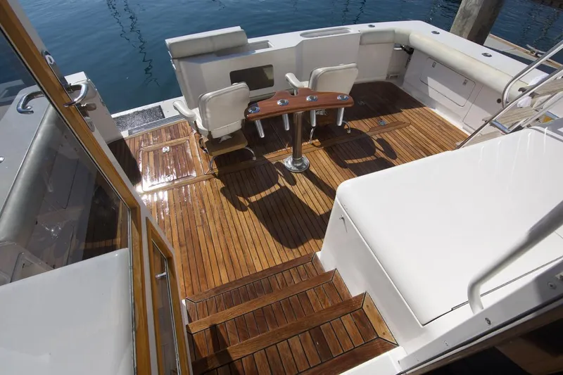 Tres Juanes Yacht Photos Pics 1997 Bertram 54 Convertible yacht deck with wooden flooring and seating area.