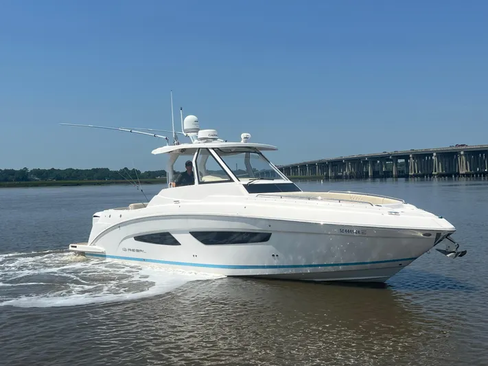  Yacht Photos Pics 2019 Regal 33 SAV boat cruising on a calm river near a bridge.