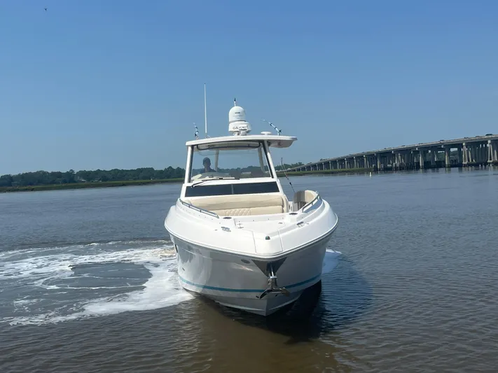  Yacht Photos Pics 2019 Regal 33 SAV boat cruising on a calm river near a bridge.