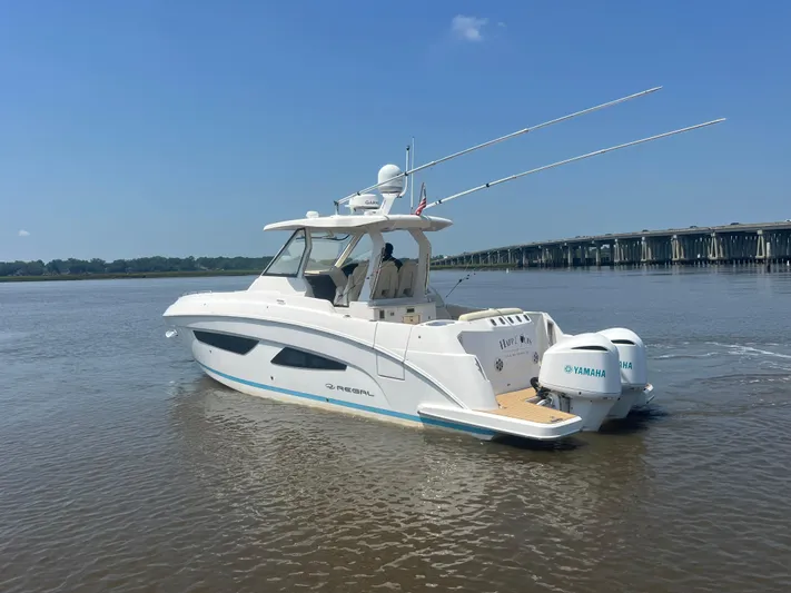  Yacht Photos Pics 2019 Regal 33 SAV boat cruising on a calm river near a bridge.