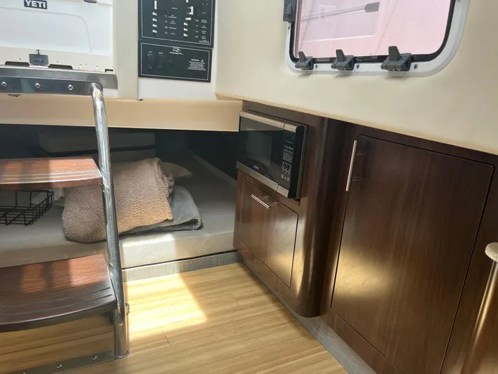  Yacht Photos Pics 2019 Regal 33 SAV interior with microwave, wooden cabinets, and cozy bedding area.