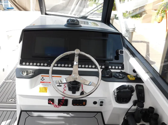 Out To Lunch Yacht Photos Pics 2019 Everglades 340 DC boat helm with dual screens, steering wheel, and navigation controls.