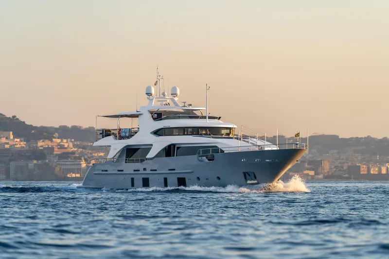 Horizon Yacht Photos Pics Luxurious 2016 Benetti 93' yacht cruising near a coastal city at sunset.