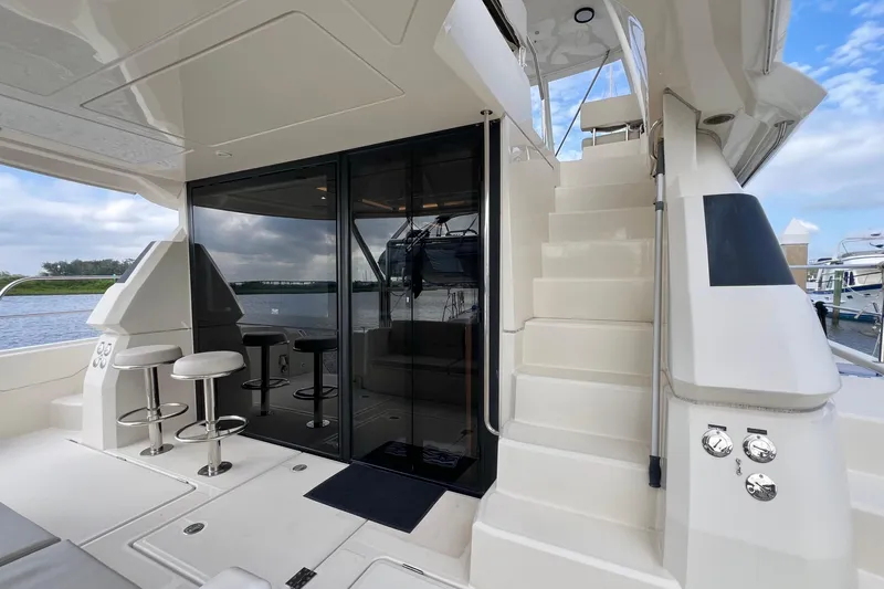 Tonga Time Yacht Photos Pics 2019 Aquila 44 yacht interior with bar stools and staircase, docked by the water.