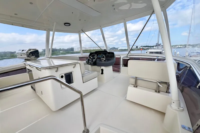 Tonga Time Yacht Photos Pics Flybridge of 2019 Aquila 44 yacht with helm station and seating, overlooking marina.