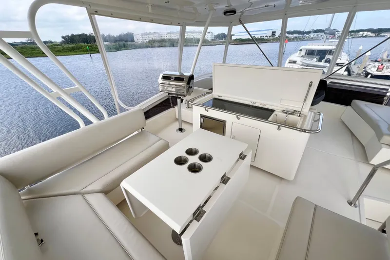 Tonga Time Yacht Photos Pics Luxurious 2019 Aquila 44 yacht interior with seating, table, and grill overlooking serene waters.