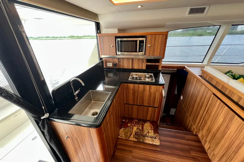 Tonga Time Yacht Photos Pics Luxurious 2019 Aquila 44 yacht kitchen with wood cabinetry, sink, stove, and microwave.