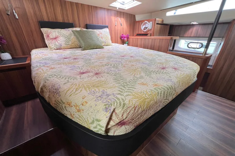 Tonga Time Yacht Photos Pics Luxurious bedroom interior of 2019 Aquila 44 yacht with floral bedding and wood paneling.