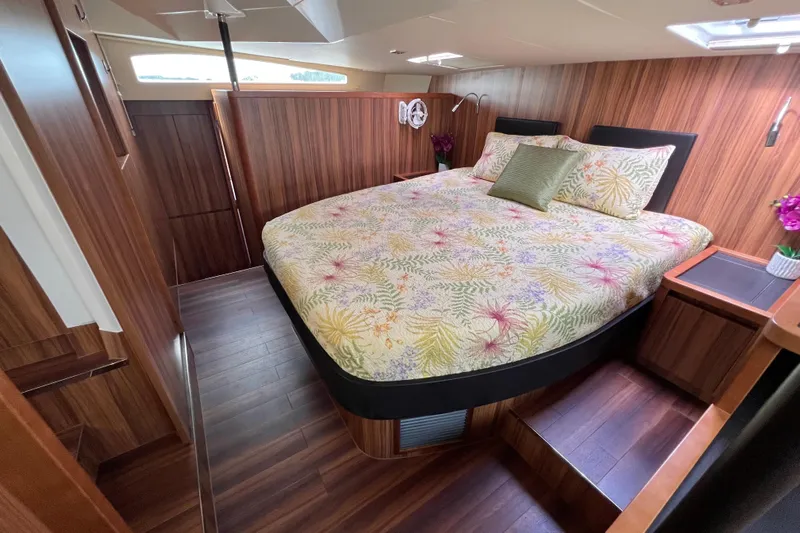 Tonga Time Yacht Photos Pics Luxurious bedroom interior of 2019 Aquila 44 yacht with floral bedding and wood paneling.