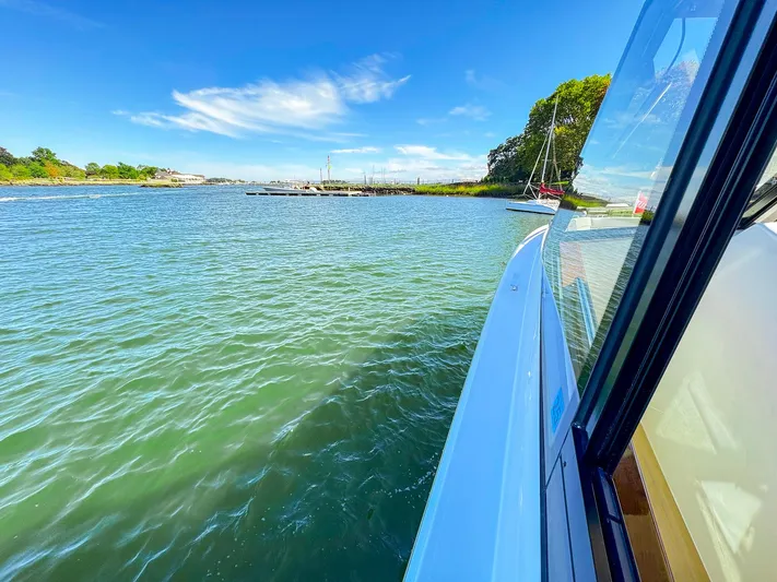 4794tw Yacht Photos Pics 2024 MJM 4 boat cruising on a sunny day near a lush shoreline.