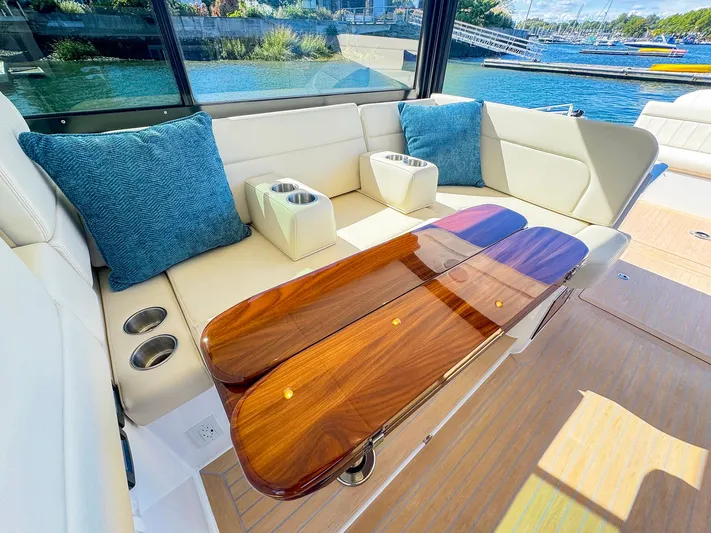 4794tw Yacht Photos Pics Luxurious seating area on 2024 MJM 4 boat with elegant wood table and blue cushions.