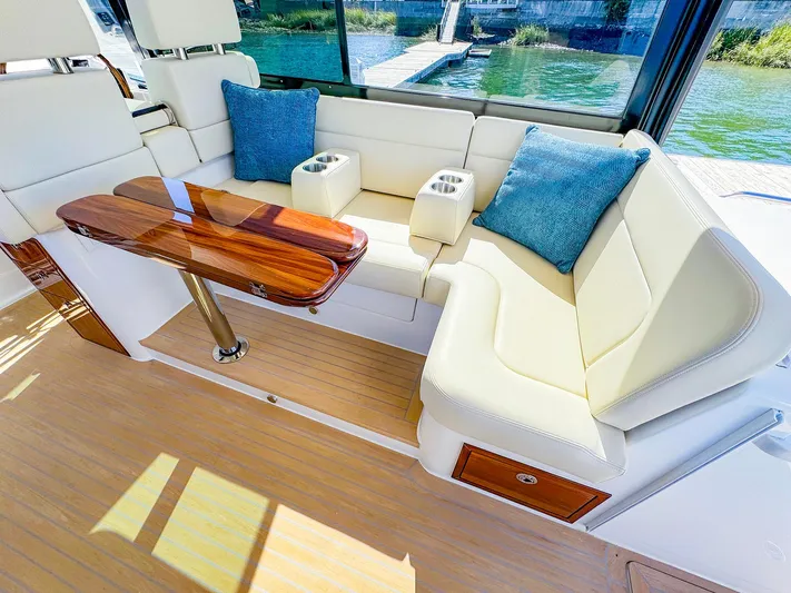 4794tw Yacht Photos Pics Luxurious seating area on 2024 MJM 4 yacht with wooden table and blue cushions.