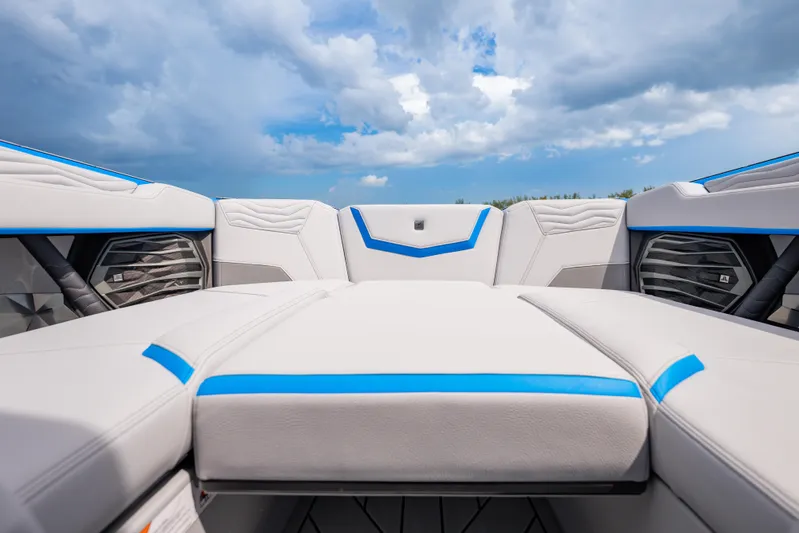  Yacht Photos Pics 2026 Nautique Super Air Nautique G23 interior with sleek white and blue upholstery under cloudy sky.