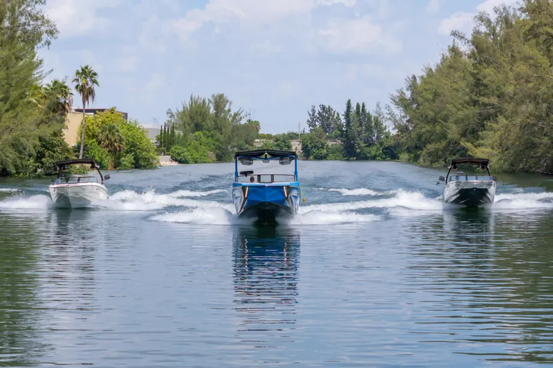  Yacht Photos Pics 2026 Nautique Super Air Nautique G23 boats cruising on a scenic waterway.