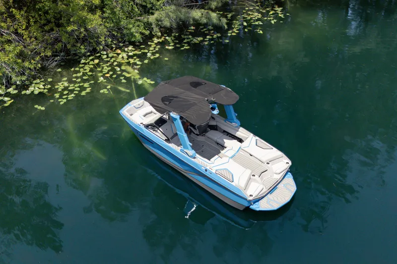  Yacht Photos Pics 2026 Nautique Super Air Nautique G23 boat on serene water surrounded by greenery.