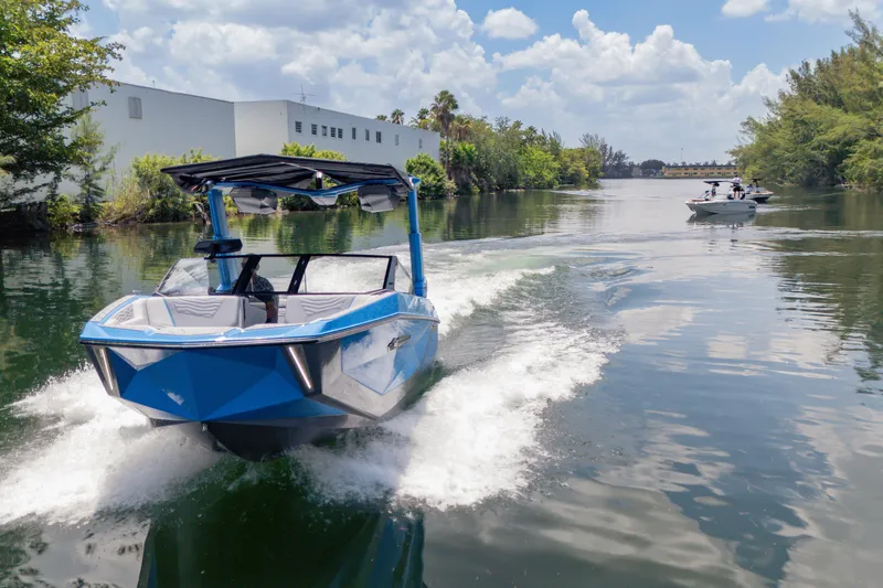  Yacht Photos Pics 2026 Nautique Super Air Nautique G23 cruising on a scenic waterway under a clear sky.