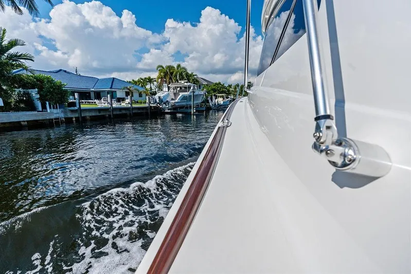 Lollipop Yacht Photos Pics 2022 Viking 48 Convertible yacht cruising along a scenic waterfront.