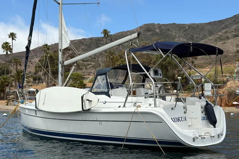 Kokua Yacht Photos Pics 2004 Hunter 33 sailboat anchored in scenic coastal waters with hills and palm trees.