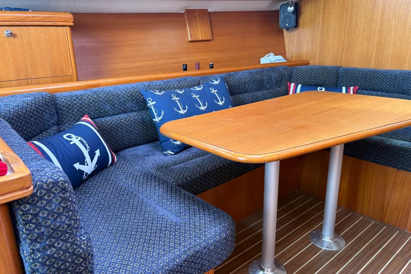 Kokua Yacht Photos Pics 2004 Hunter 33 yacht interior with wooden table and anchor-themed cushions.