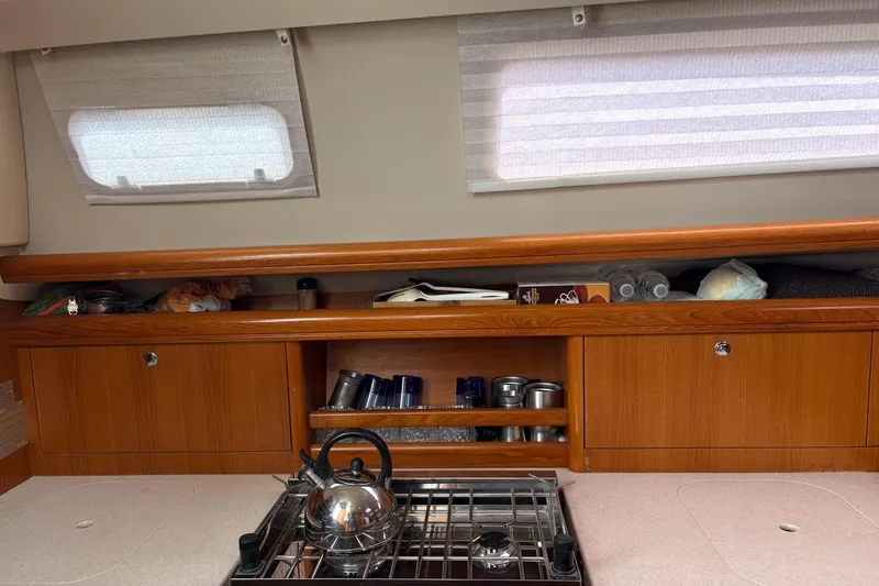 Kokua Yacht Photos Pics Interior of a 2004 Hunter 33 sailboat galley with stove and wooden cabinets.