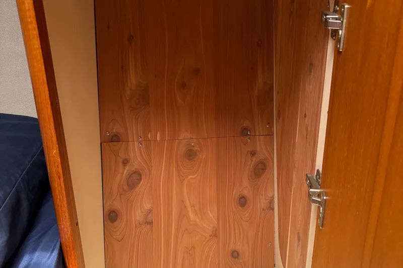 Kokua Yacht Photos Pics Wooden interior cabinet of a 2004 Hunter 33 sailboat, featuring metal hinges.