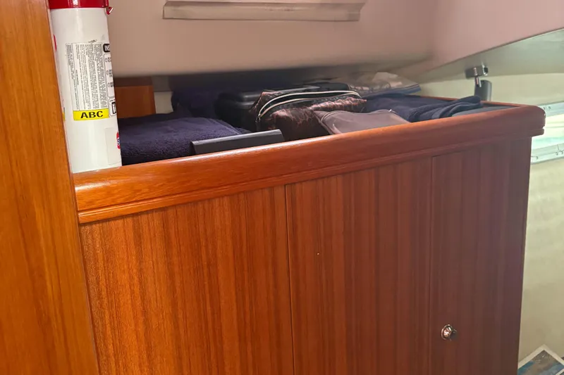 Kokua Yacht Photos Pics Wooden cabinet with clothes and fire extinguisher inside a 2004 Hunter 33 boat interior.