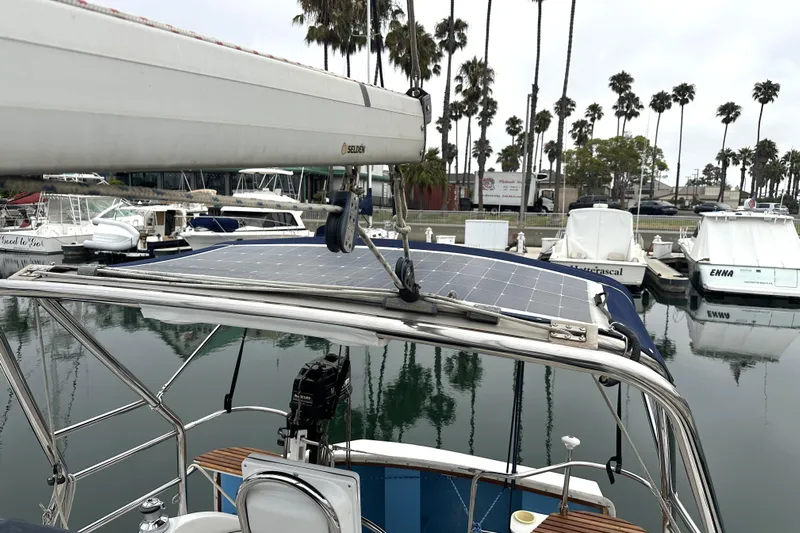 Kokua Yacht Photos Pics 2004 Hunter 33 sailboat with solar panels docked in a marina, surrounded by palm trees.