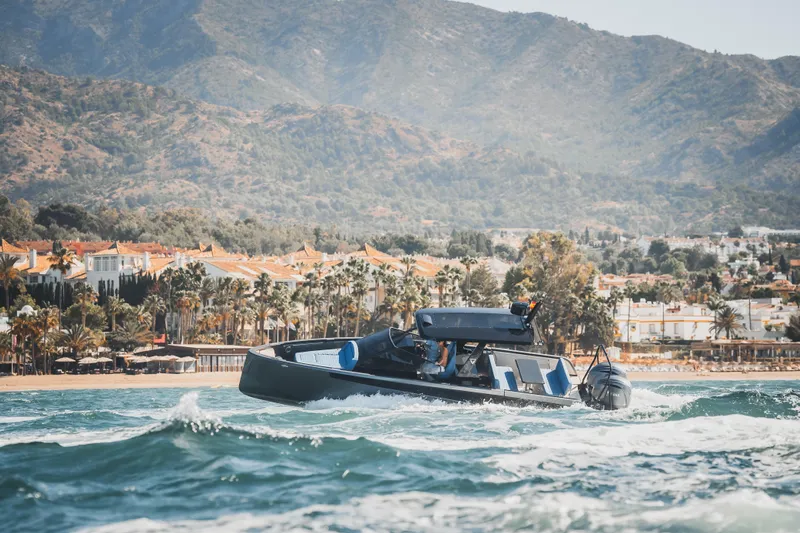  Yacht Photos Pics 2026 Virtue V10 T-Top boat cruising near scenic coastal town with mountains.