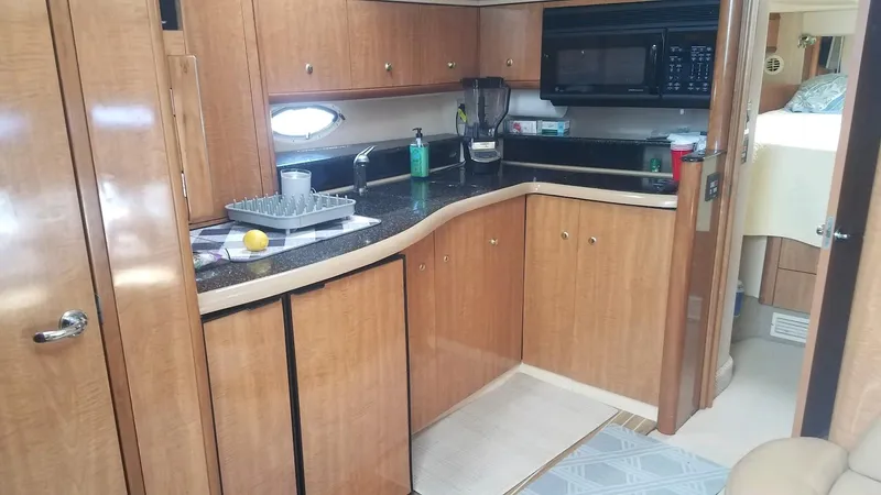 Instant Karma Yacht Photos Pics 2002 Maxum 4200 SY yacht kitchen with wood cabinets and black countertops.