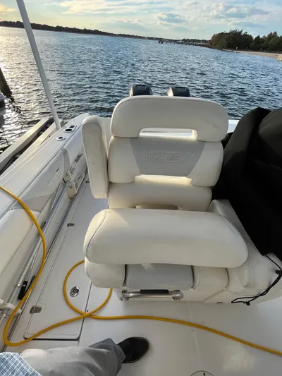  Yacht Photos Pics 2011 Boston Whaler 320 Outrage Cuddy Cabin with white seating, docked by a scenic waterway.