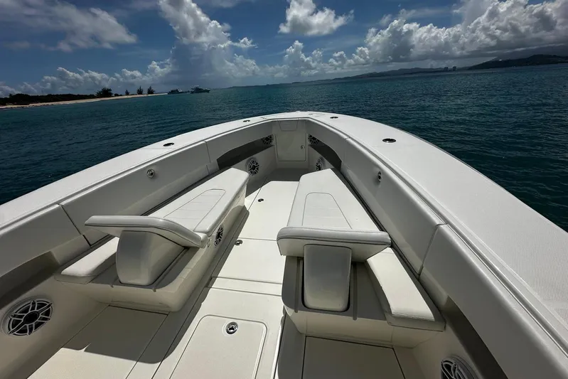  Yacht Photos Pics 2022 SeaVee 390Z boat interior with cushioned seating, on calm ocean waters under a cloudy sky.