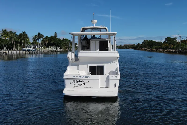 Aloha Spirit Yacht Photos Pics 2005 Carver 41 Cockpit Motor Yacht on a serene waterway, surrounded by lush greenery.
