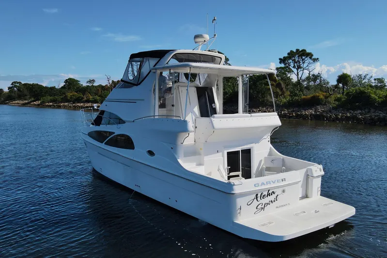 Aloha Spirit Yacht Photos Pics 2005 Carver 41 Cockpit Motor Yacht on serene water, surrounded by lush greenery.