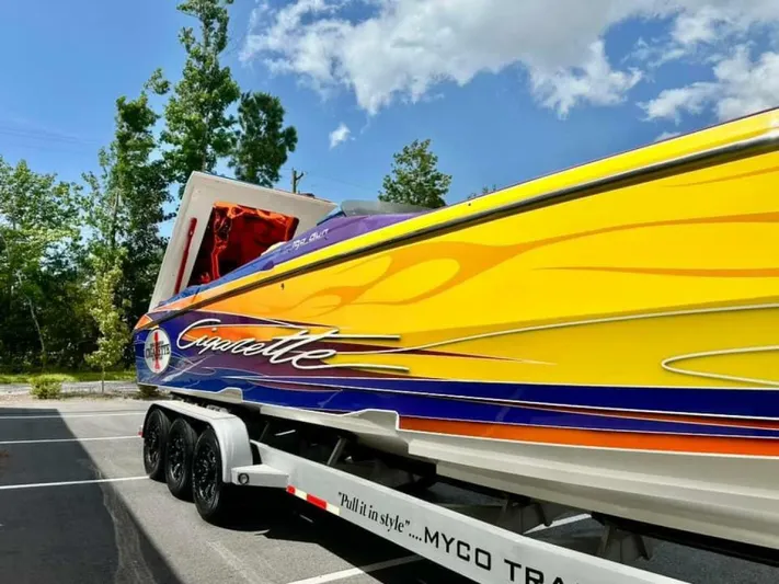 On Your Mark Yacht Photos Pics 2005 Cigarette 39 Top Gun speedboat with vibrant yellow and orange design on trailer.