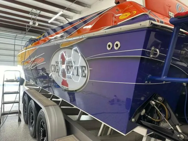 On Your Mark Yacht Photos Pics 2005 Cigarette 39 Top Gun speedboat in garage, vibrant blue and orange design, on trailer.