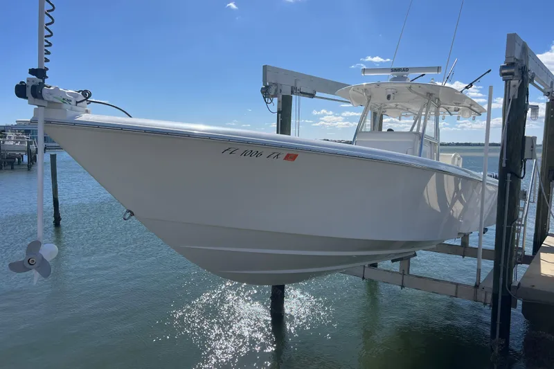  Yacht Photos Pics 2023 Contender 39 ST boat on lift, docked by the water under a clear blue sky.