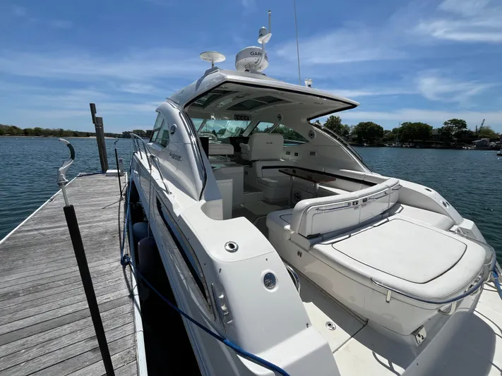 Feeling Nauti Yacht Photos Pics 2011 Sea Ray 470 Sundancer yacht docked by a serene lake under a clear blue sky.