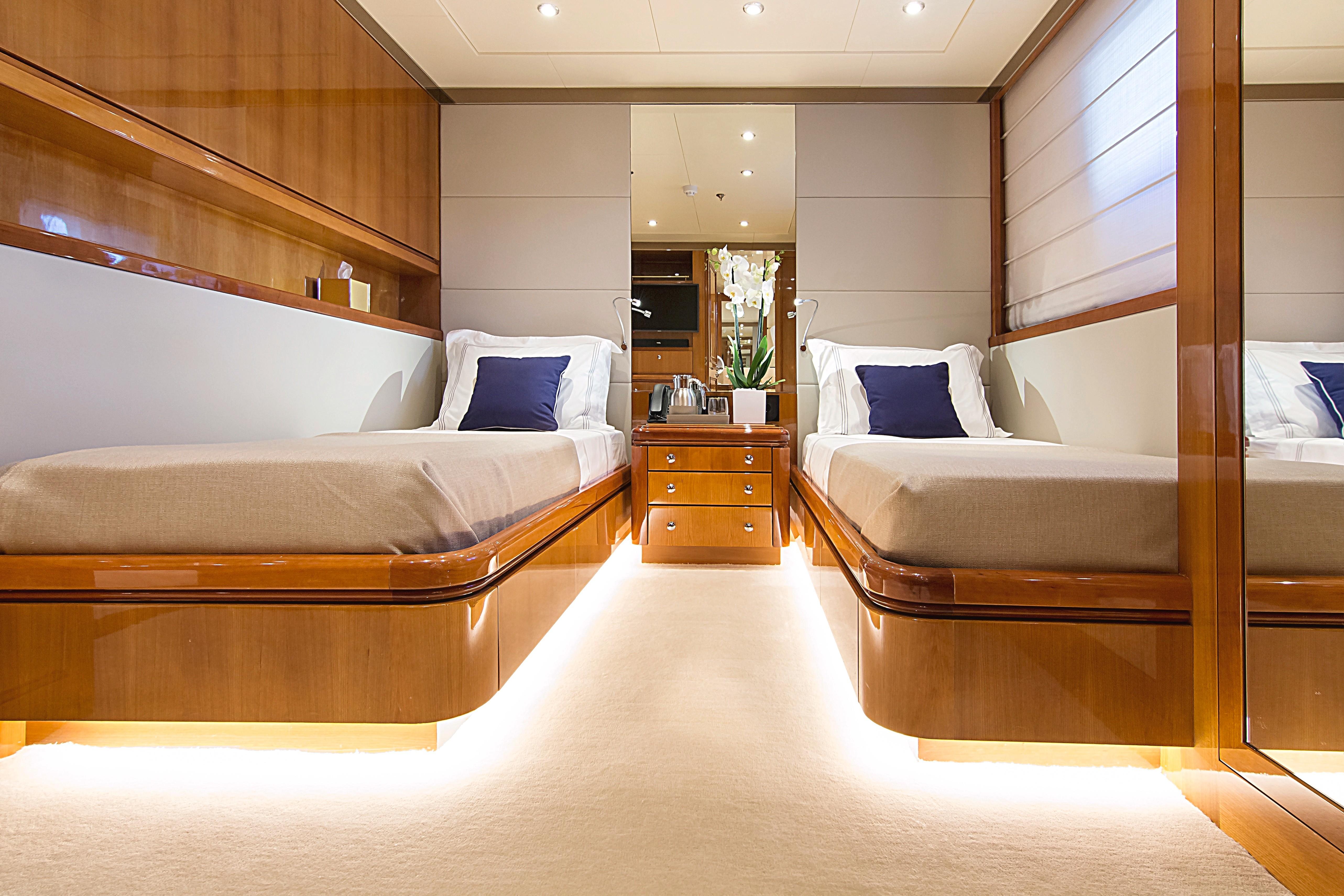 Luxurious twin bedroom on 1999 Codecasa 50m Motoryacht, featuring elegant wood finishes and ambient lighting.