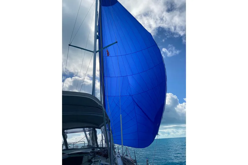 Waterfall II Yacht Photos Pics Sailing yacht Beneteau Oceanis 44 CC, 1994, with vibrant blue spinnaker against cloudy sky.