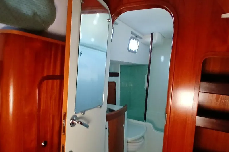 Waterfall II Yacht Photos Pics Interior of 1994 Beneteau Oceanis 44 CC yacht, featuring wooden cabinetry and bathroom area.