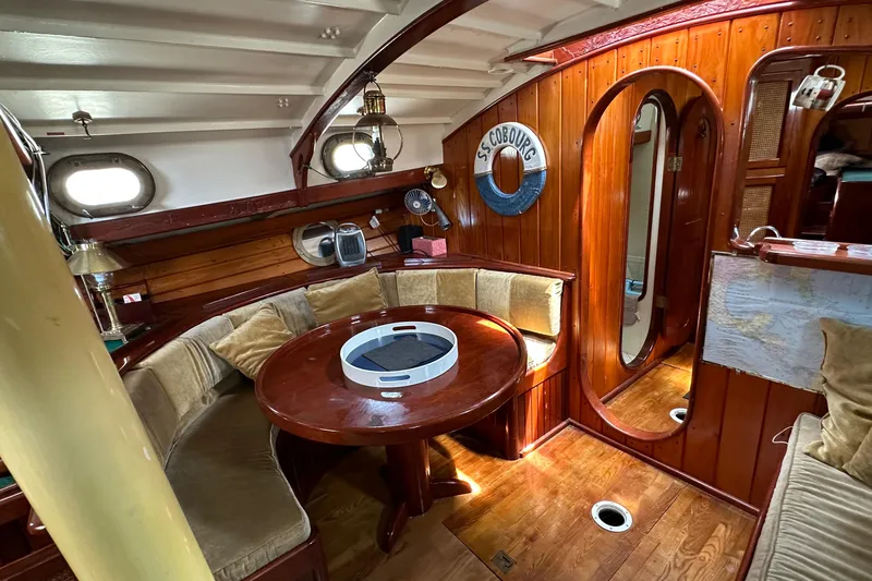 Interlude X Yacht Photos Pics Interior of 1985 Custom Thomas Colvin "Pipistrelle" sailboat with wooden furnishings and round table.