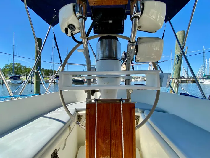 Encore Yacht Photos Pics Cockpit view of 1998 Pacific Seacraft 37 sailboat with steering wheel and marina background.