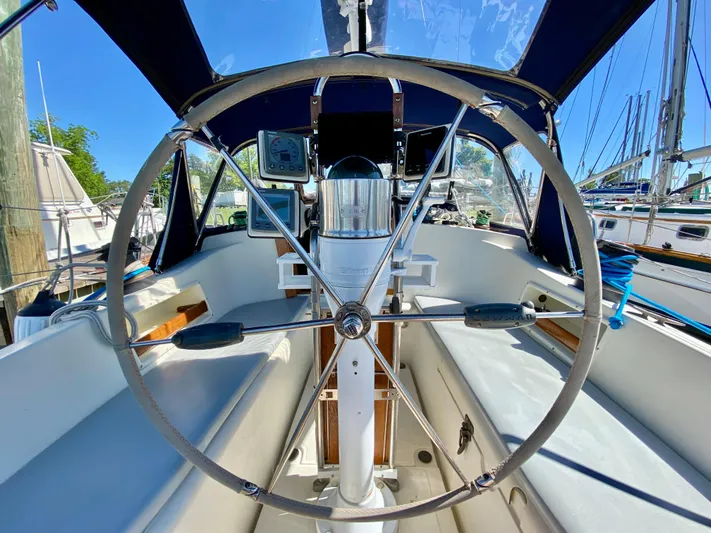 Encore Yacht Photos Pics Steering wheel of a 1998 Pacific Seacraft 37 sailboat, docked in a marina.