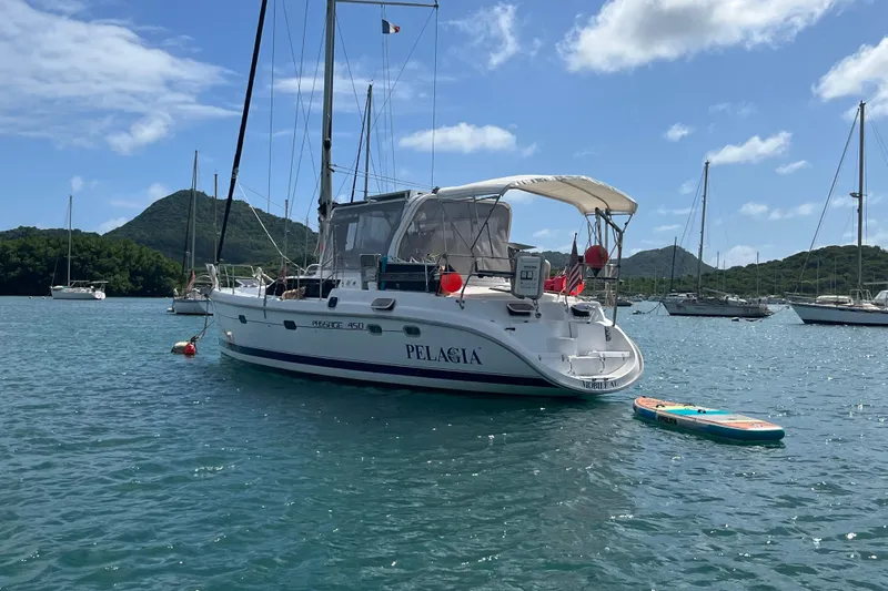 Pelagia Yacht Photos Pics Hunter Passage 450 sailboat anchored in scenic bay, 1998 model, with paddleboard nearby.