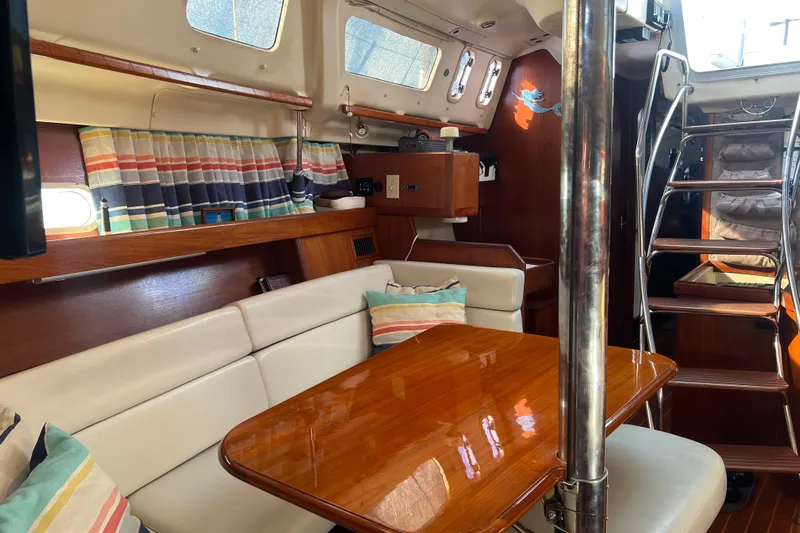 Pelagia Yacht Photos Pics Interior of 1998 Hunter Passage 450 sailboat with cozy seating and striped curtains.