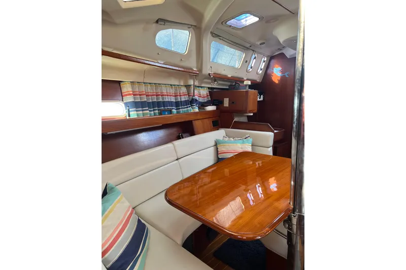 Pelagia Yacht Photos Pics Interior of 1998 Hunter Passage 450 sailboat with polished wood table and striped cushions.