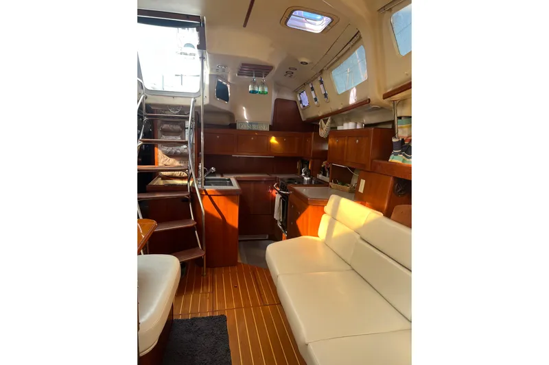 Pelagia Yacht Photos Pics Interior of 1998 Hunter Passage 450 sailboat with wooden cabinetry and white seating.
