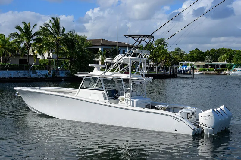 Denied Yacht Photos Pics 2021 Yellowfin 42 boat on calm water, surrounded by palm trees and houses.