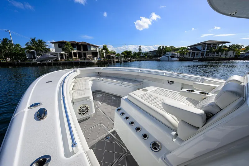 Denied Yacht Photos Pics 2021 Yellowfin 42 boat with luxurious seating, docked near waterfront homes under a clear blue sky.