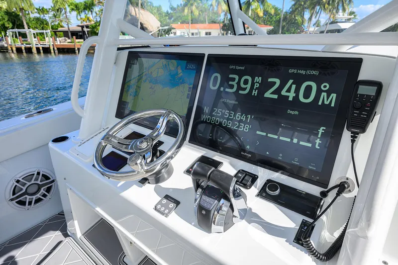 Denied Yacht Photos Pics 2021 Yellowfin 42 boat dashboard with navigation screens and steering wheel, dockside view.